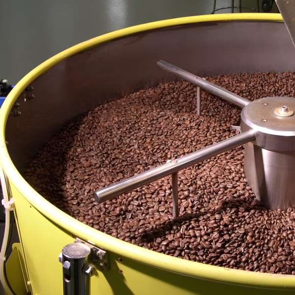 Chicchi di caffè tostati in una tostatrice professionale.
